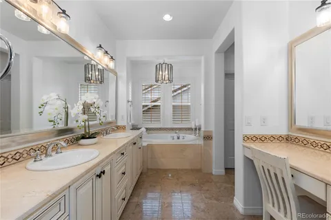 a spacious bathroom with a granite countertop double vanity sink a mirror and a bathtub