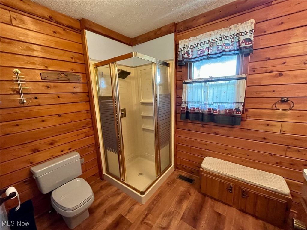 5991 Sandy Ridge Road Southeast Tippecanoe, OH 44699 - Photo 23 of 34 Bathroom with wood walls, a textured ceiling, wood finished floors, and a stall shower