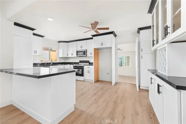 a kitchen with stainless steel appliances granite countertop a refrigerator a stove a sink dishwasher and white cabinets with wooden floor