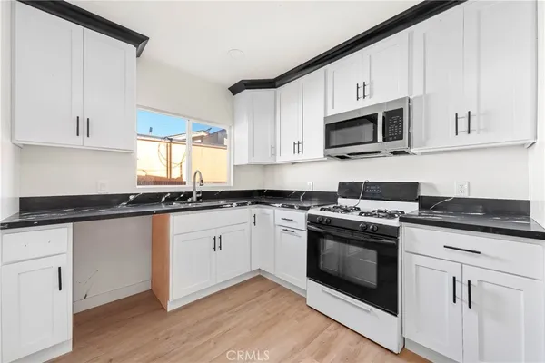 a kitchen with granite countertop white cabinets and white appliances