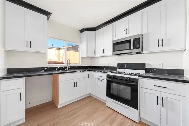 a kitchen with granite countertop white cabinets and white appliances