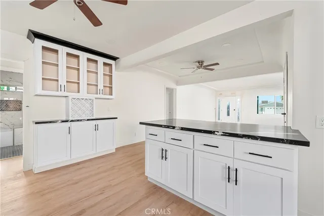 a kitchen with granite countertop white cabinets and wooden floor