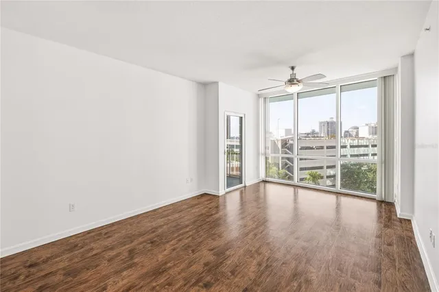 an empty room with wooden floor and windows