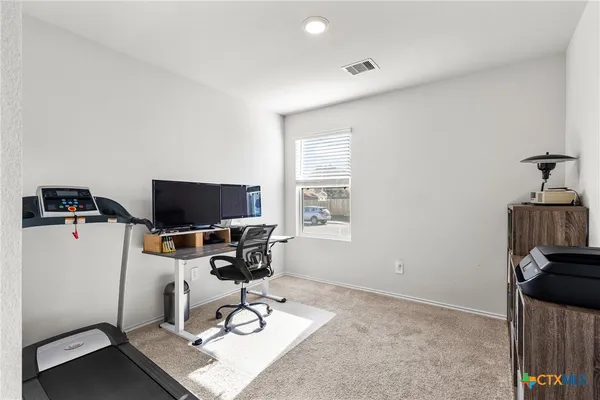 a view of a workspace with furniture and a window