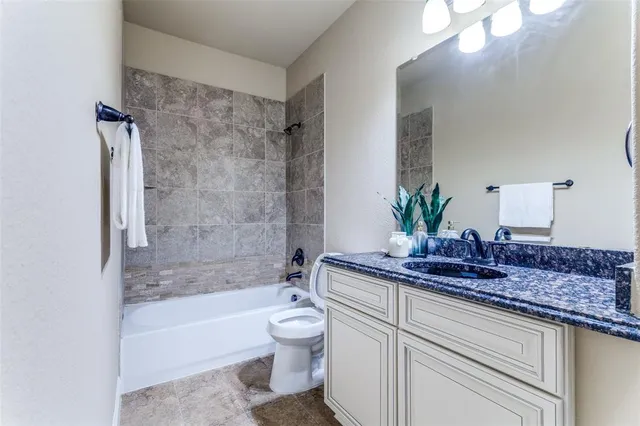 a bathroom with a granite countertop sink a toilet and bathtub