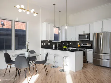a kitchen with stainless steel appliances a dining table chairs stove and refrigerator
