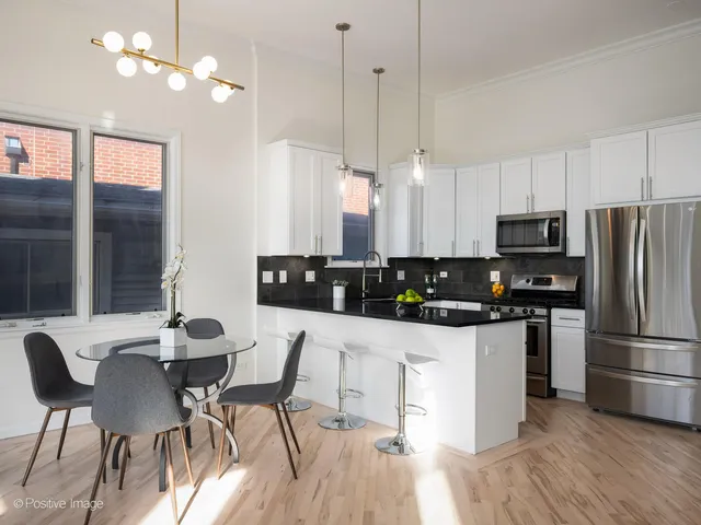 a kitchen with stainless steel appliances a dining table chairs stove and refrigerator