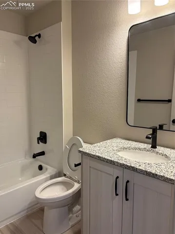 a bathroom with a granite countertop sink toilet and mirror