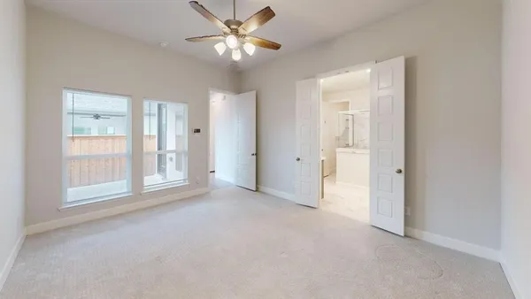an empty room with chandelier fan and windows