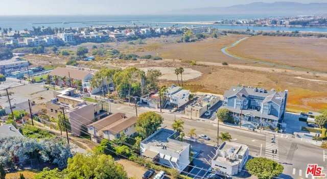 an aerial view of ocean and residential houses with outdoor space