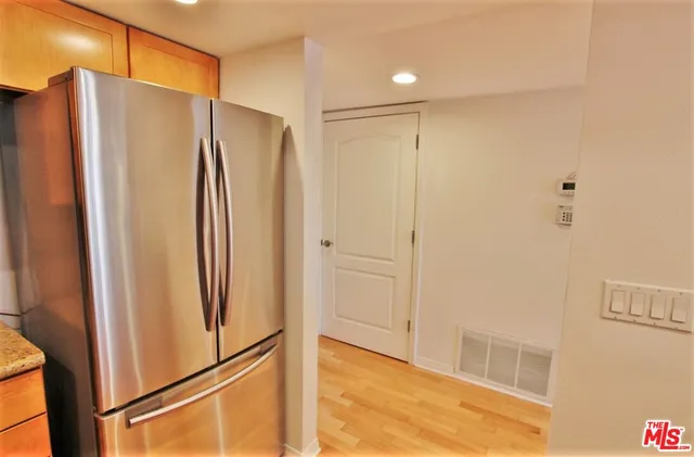 a view of a refrigerator in kitchen and white cabinets