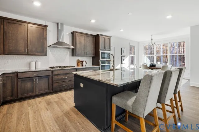 a kitchen with stainless steel appliances granite countertop a table chairs sink refrigerator and cabinets