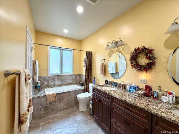 a bathroom with a granite countertop sink mirror and a bathtub