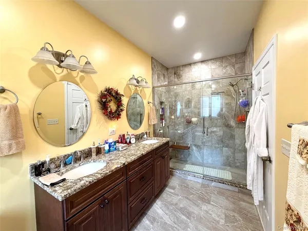 a bathroom with a granite countertop sink a mirror and a shower