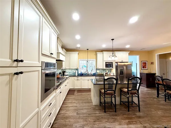 a kitchen with stainless steel appliances kitchen island granite countertop a table chairs sink and cabinets