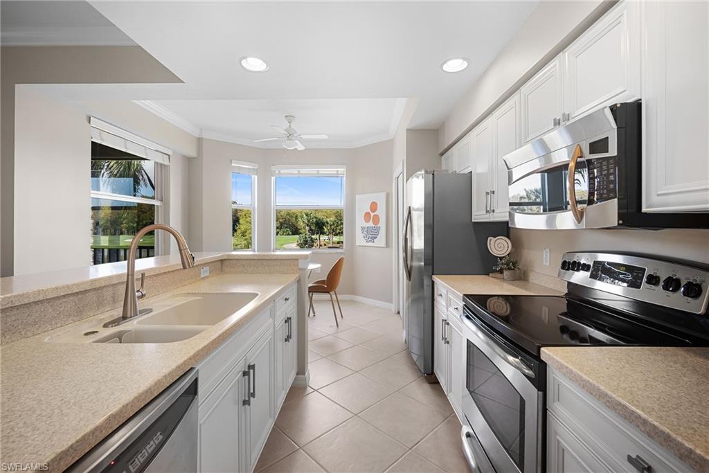 10265 Heritage Bay Boulevard, Unit 622 Naples, FL 34120 - Photo 17 of 50 a kitchen with granite countertop a sink stainless steel appliances and cabinets