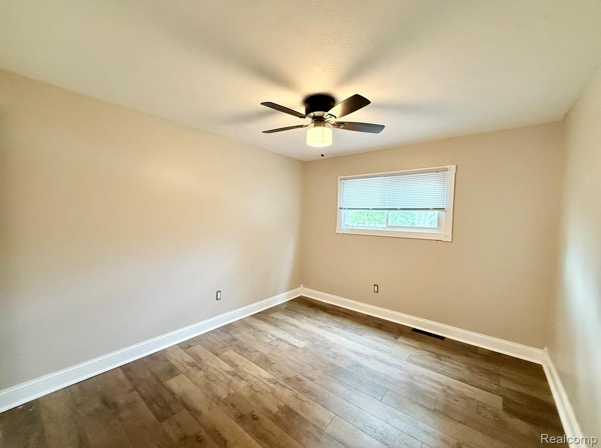 2360 Oklahoma Avenue Rochester, MI 48309 - Photo 27 of 36 Room featuring wood-finish flooring, neutral wall tones, a ceiling fan with integrated lighting, white baseboards, and a window with blinds