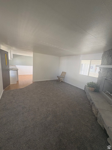 1111 North 2000 West, Unit 293 Farr West, UT 84404 - Photo 13 of 13 Spacious living area featuring neutral carpeting, white walls, a stone fireplace with a substantial hearth, and a large window