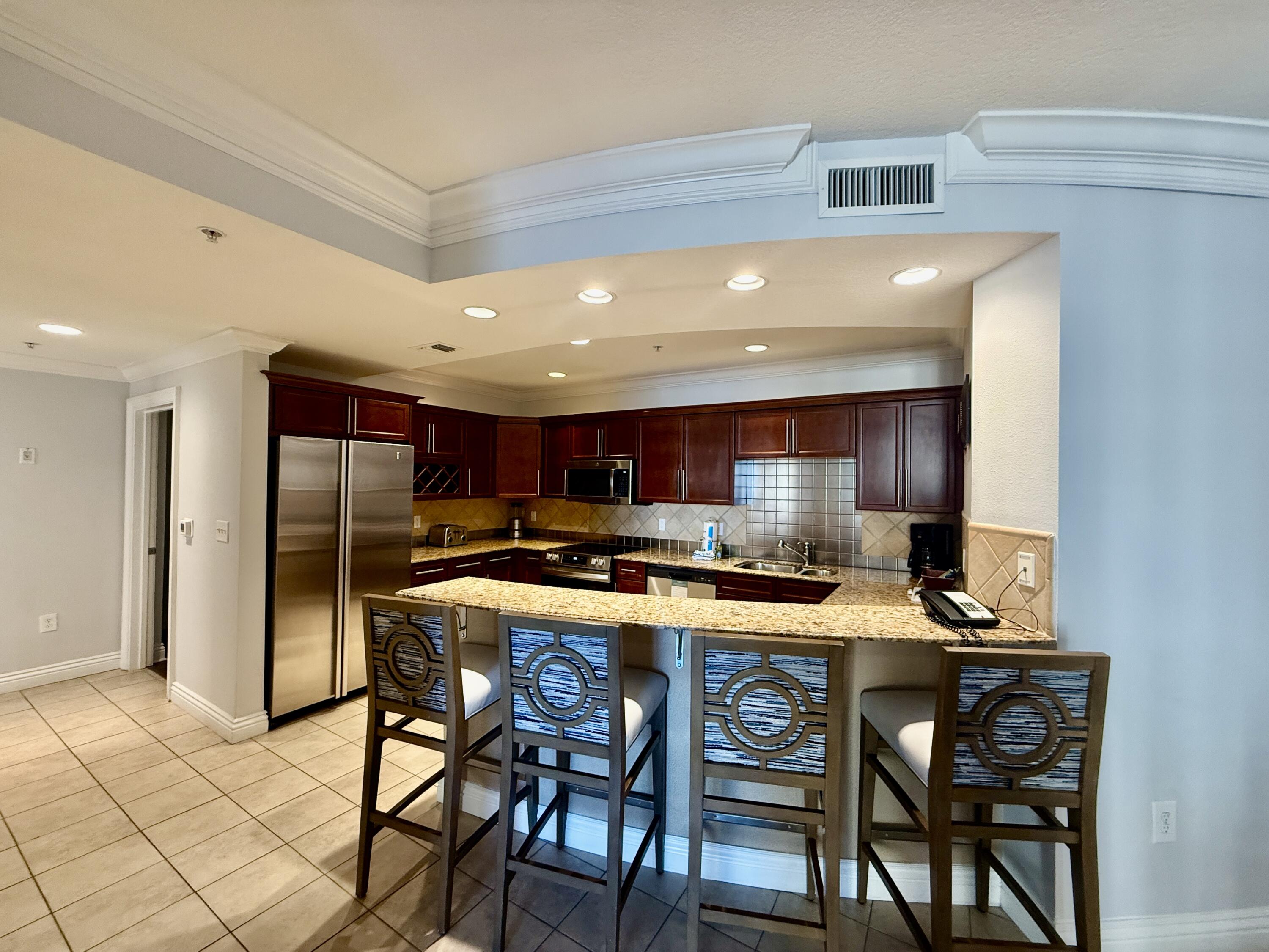 10 Harbor Boulevard, Unit E803G Destin, FL 32541 - Photo 5 of 28 a kitchen with stainless steel appliances kitchen island granite countertop a table chairs sink and cabinets