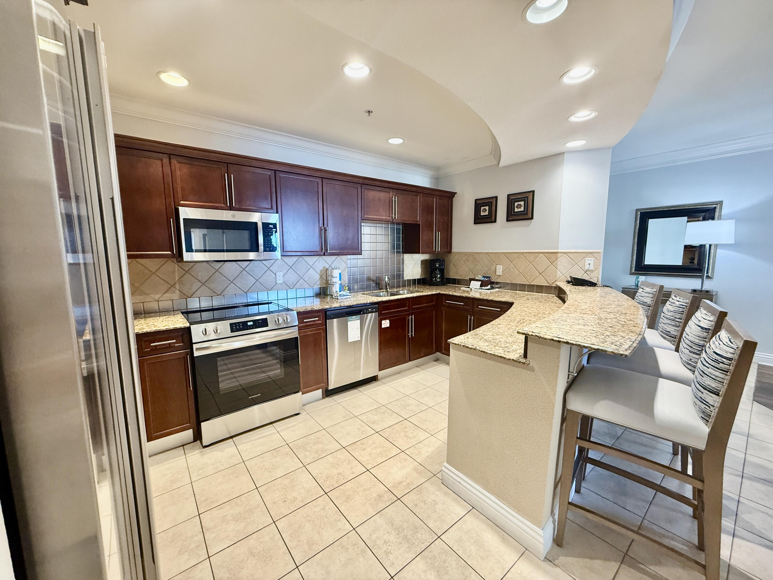 10 Harbor Boulevard, Unit E803G Destin, FL 32541 - Photo 6 of 28 a kitchen with stainless steel appliances granite countertop a stove top oven a sink a dining table and chairs