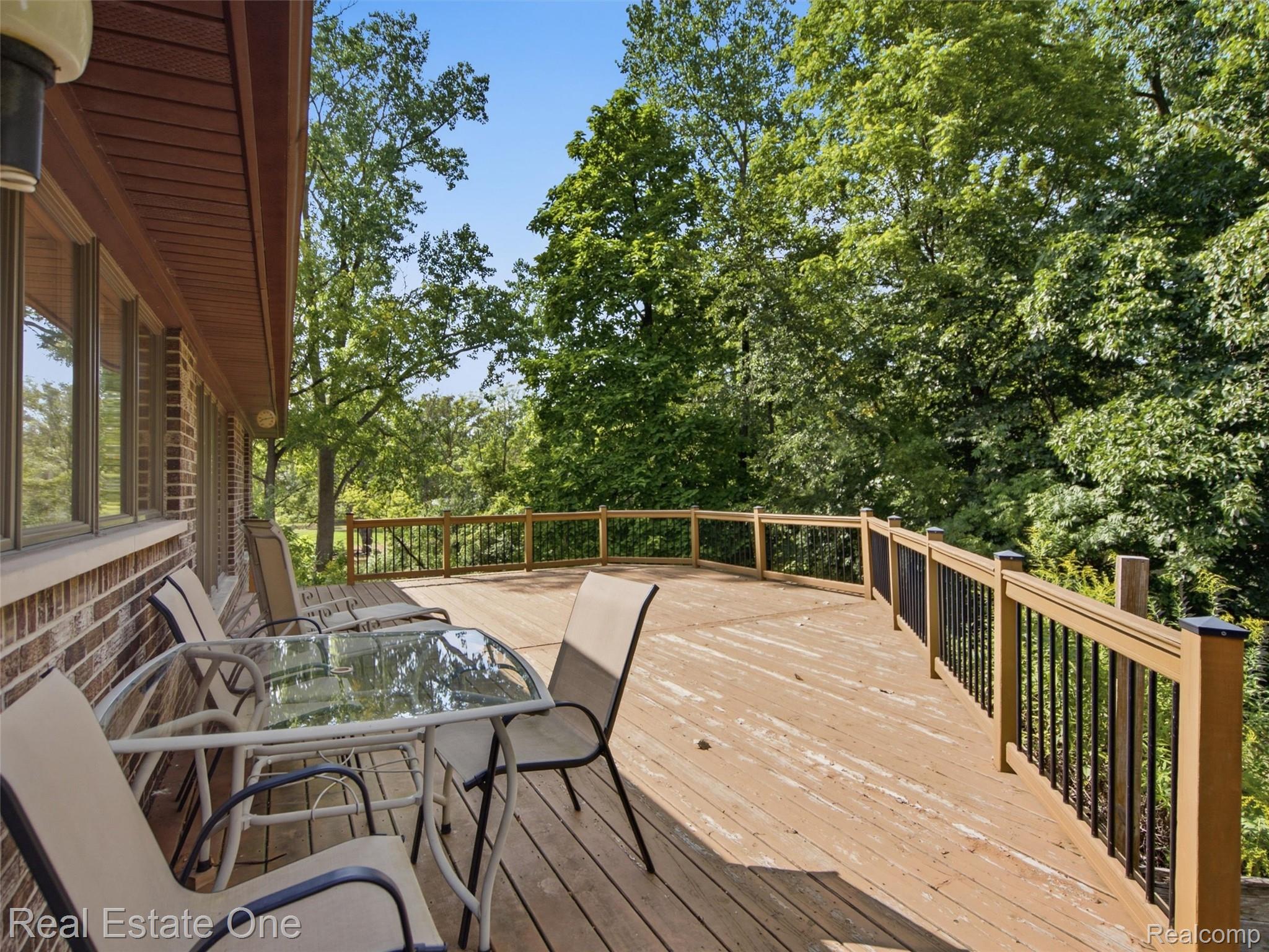 2626 West Wattles Road Troy, MI 48098 - Photo 44 of 65 Expansive composite deck featuring wood-finish decking, black metal railings, and seating areas overlooking mature landscaping and tree canopy