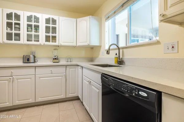 a kitchen with stainless steel appliances granite countertop white cabinets sink and window