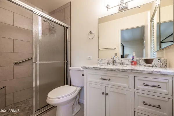 a bathroom with a granite countertop toilet sink and mirror
