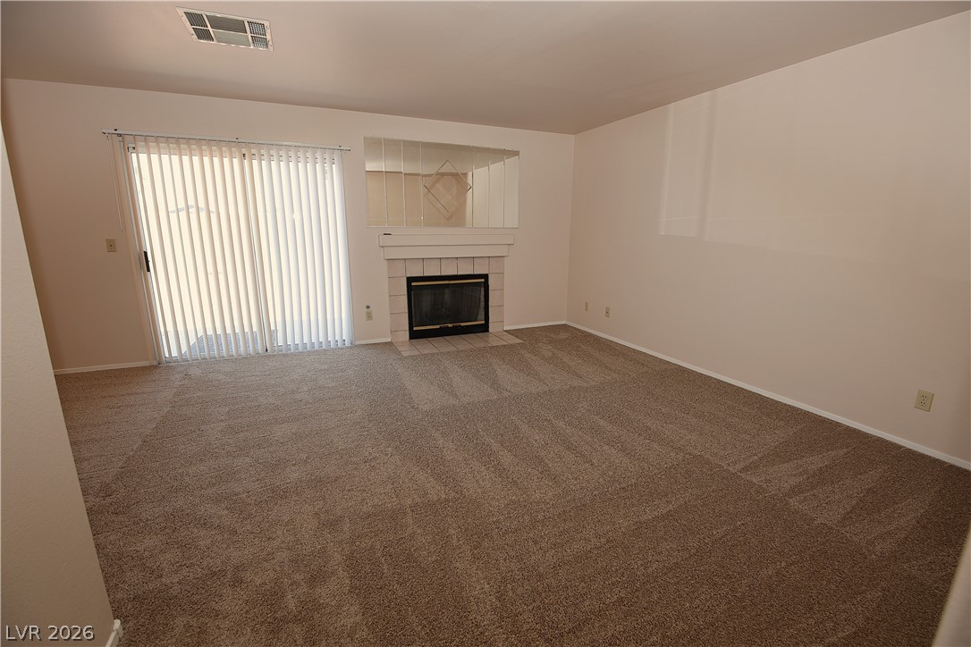 8220 Maplestar Road Las Vegas, NV 89128 - Photo 10 of 29 A well-proportioned living room featuring a cozy fireplace and convenient sliding glass door access.