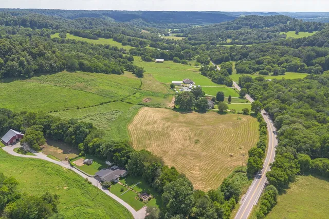 an aerial view of a residential houses with outdoor space and trees all around