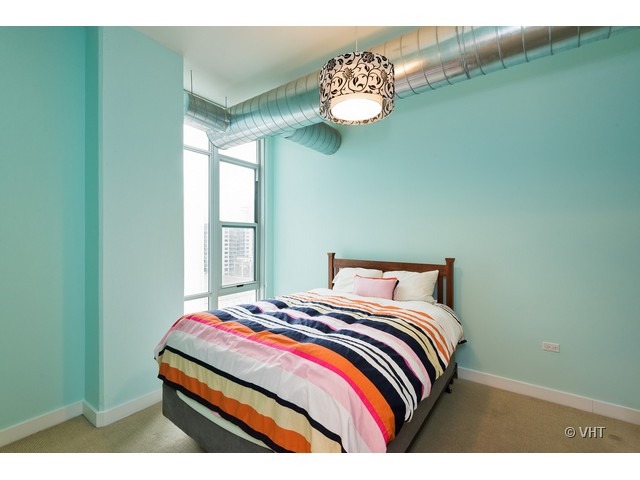 901 West Madison Street, Unit 905 Chicago, IL 60607 - Photo 6 of 10 a bedroom with a bed and a chandelier