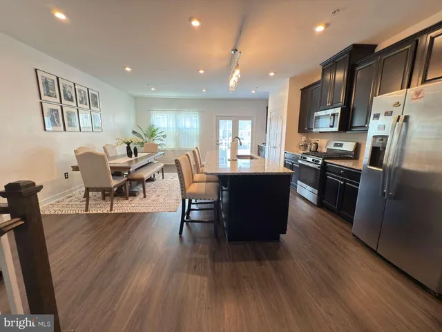 a living room with stainless steel appliances granite countertop furniture wooden floor and a kitchen view