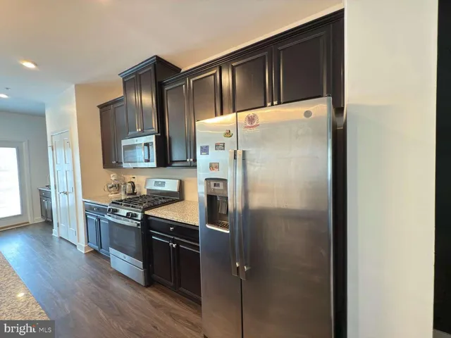 a kitchen with granite countertop stainless steel appliances a refrigerator a stove top oven and sink