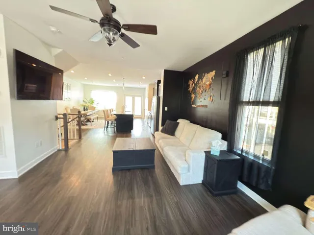 a living room with couches and a flat screen tv with kitchen view