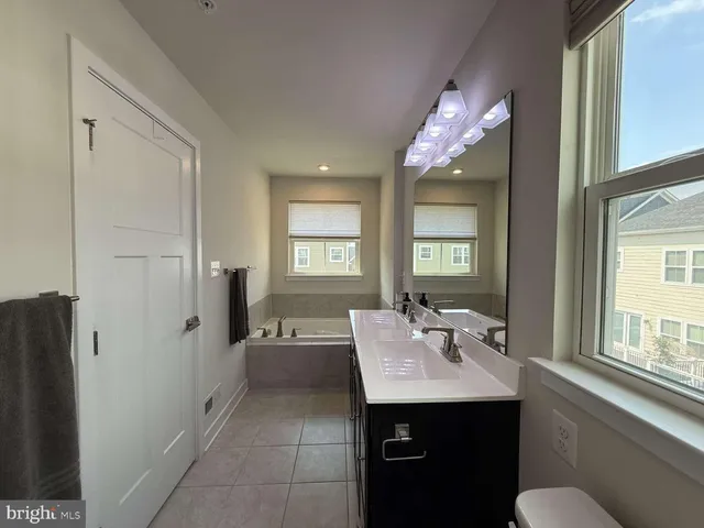 a bathroom with a sink vanity granite tub and a mirror