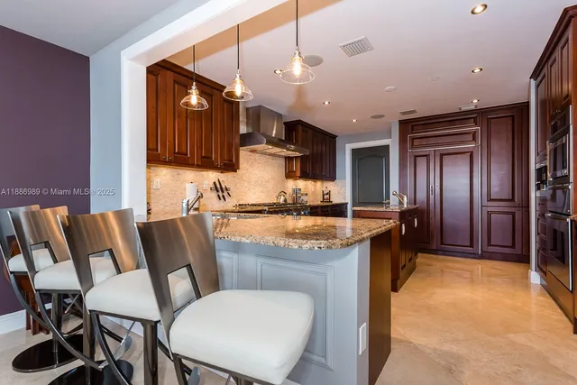 a kitchen with granite countertop a sink cabinets stainless steel appliances and a chandelier