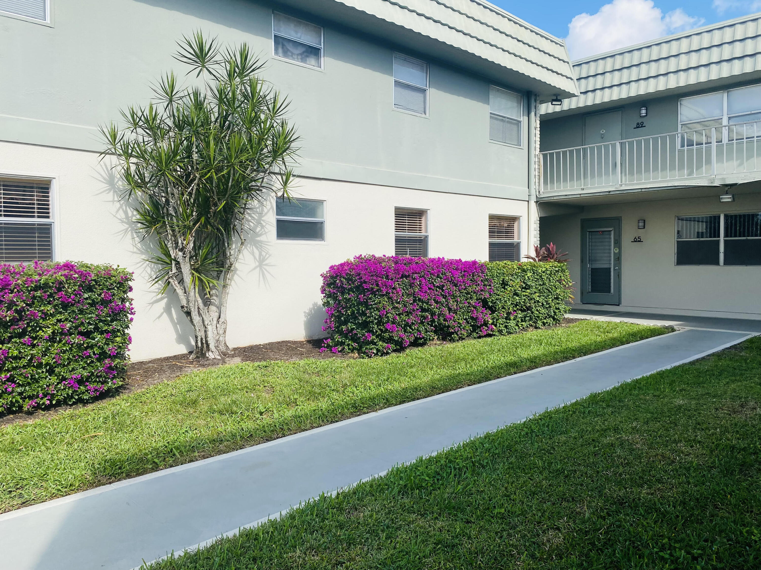 64 Flanders B, Unit 64 Delray Beach, FL 33484 - Photo 20 of 35 a front view of a house with a garden and yard