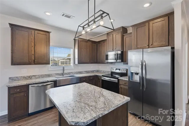 a kitchen with granite countertop a sink refrigerator and cabinets