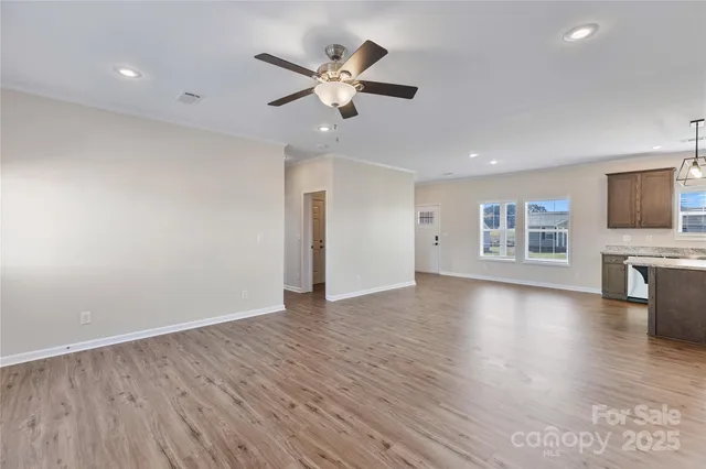 a view of an empty room with a window and a kitchen