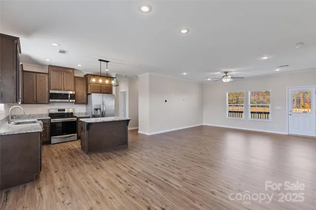 a large kitchen with stainless steel appliances kitchen island granite countertop a stove a sink and a refrigerator