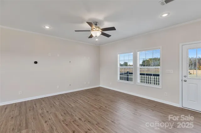 a view of an empty room with a window and wooden floor