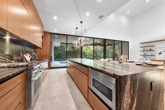 a kitchen with kitchen island granite countertop a stove and a large window