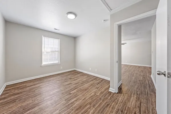 an empty room with wooden floor and windows