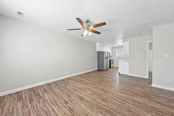 a view of an empty room with a window and wooden floor