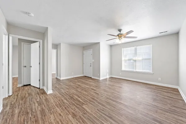 an empty room with wooden floor and windows