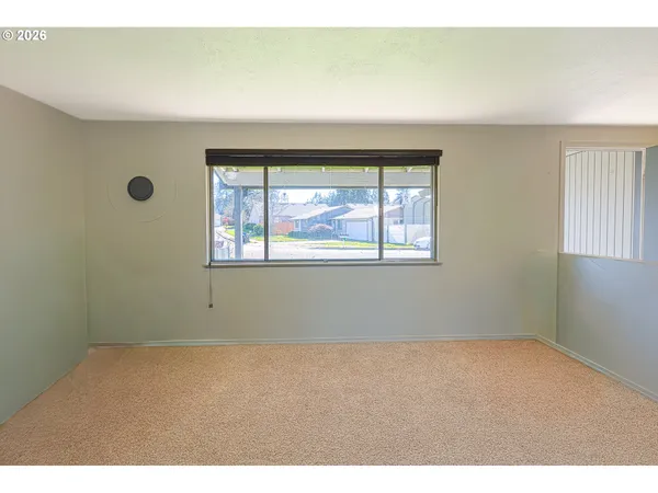 a view of an empty room with window and kitchen view