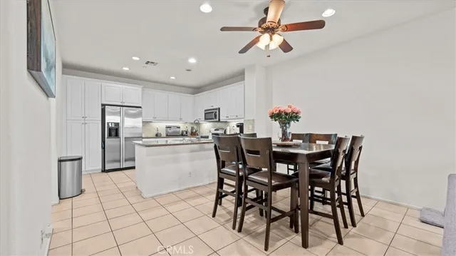 a kitchen with stainless steel appliances a dining table chairs and white cabinets