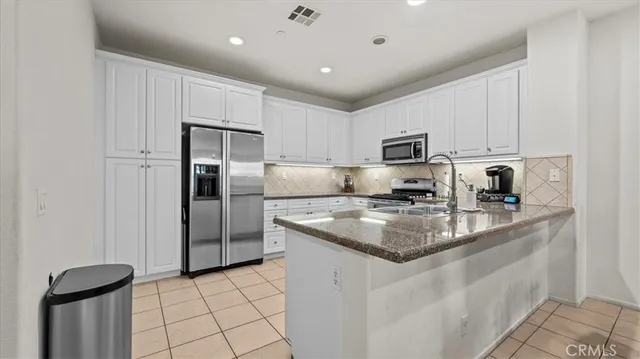 a kitchen with stainless steel appliances granite countertop a refrigerator a sink a stove a microwave and a refrigerator