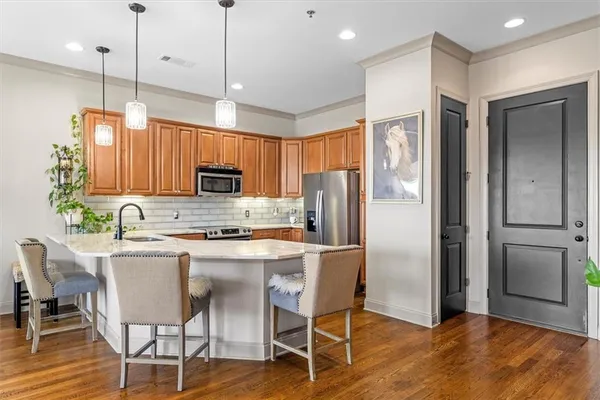 a kitchen with stainless steel appliances granite countertop a refrigerator a stove top oven a sink dishwasher and a refrigerator with wooden floor
