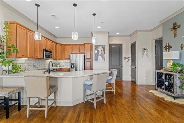 a kitchen with stainless steel appliances a dining table chairs stove refrigerator and cabinets