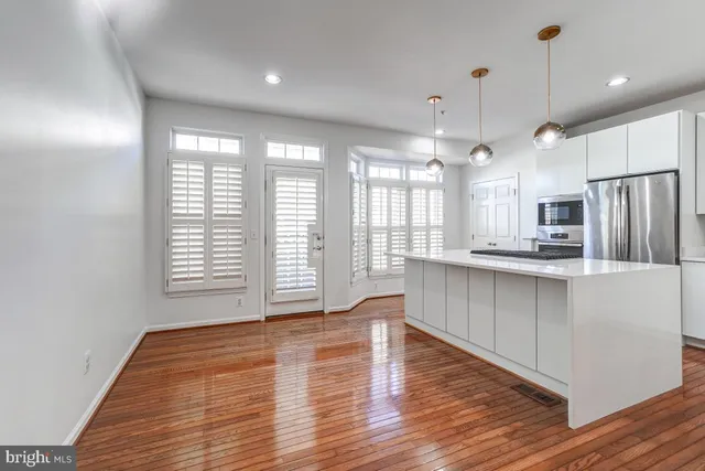 a kitchen with stainless steel appliances granite countertop a refrigerator a sink dishwasher a stove and white cabinets with wooden floor